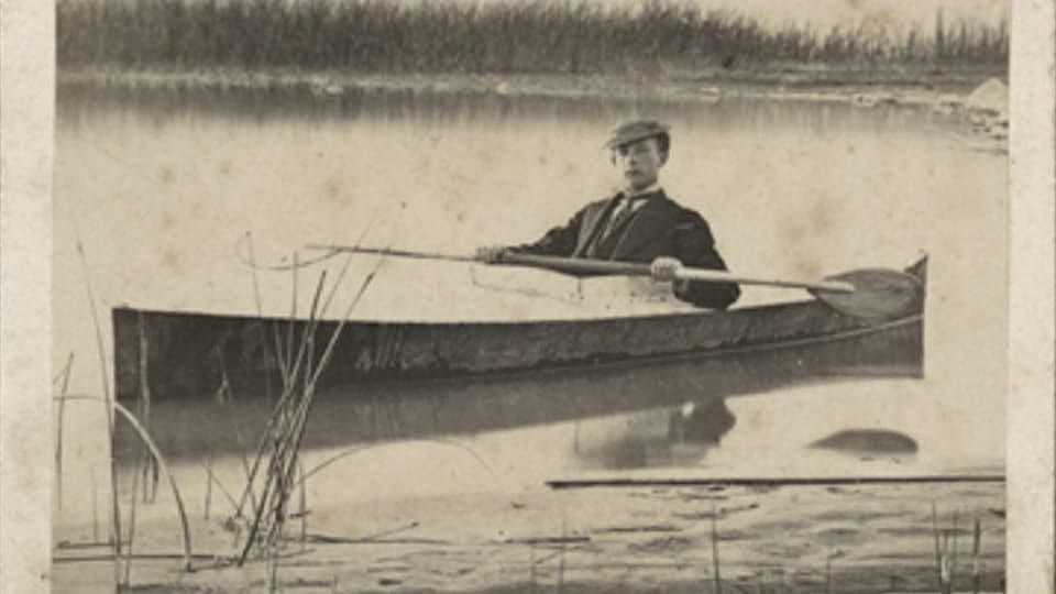 Foto des Jungen im Anzug auf einem Kajak im See.