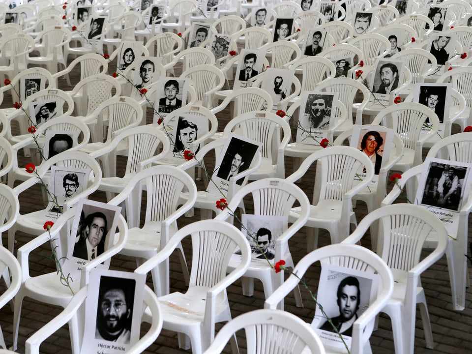 Fotos und rote Nelken auf Plastikstühlen erinnern an die Opfer der Diktatur.