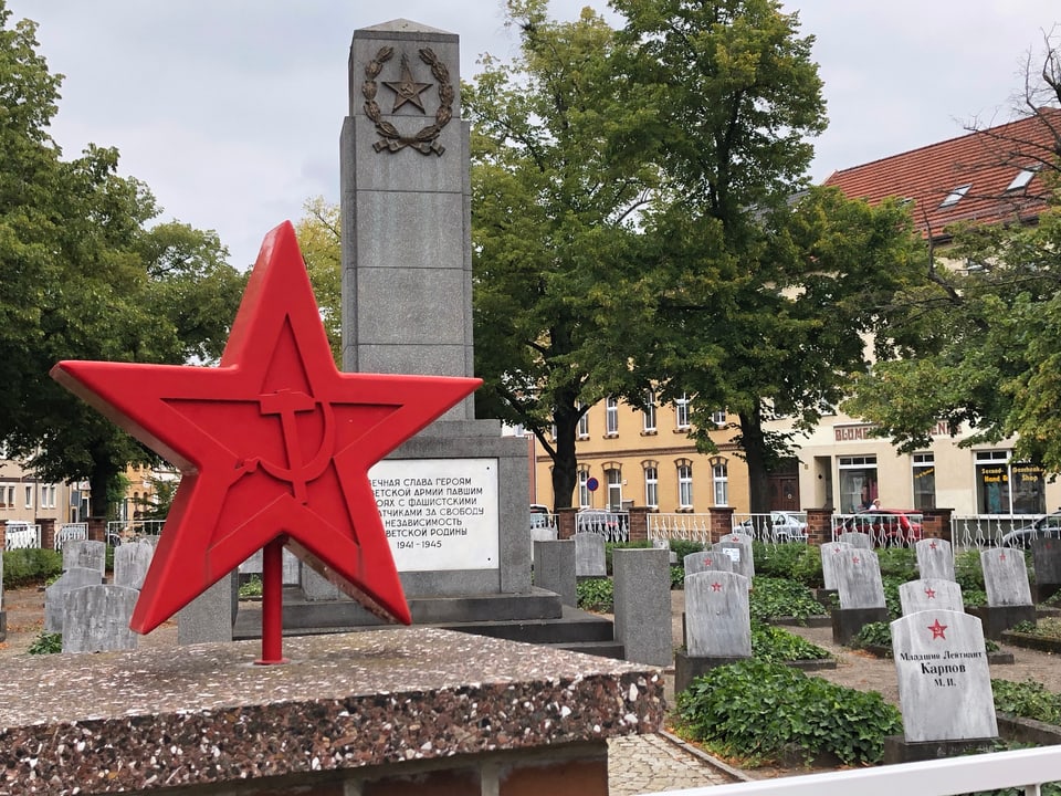 Gräber mit rotem Stern. Davor ein roter Stern mit Hammer und Sichel als Zeichen der Sowjetunion.