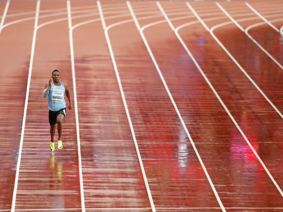 Athlet läuft allein auf regennasser Bahn