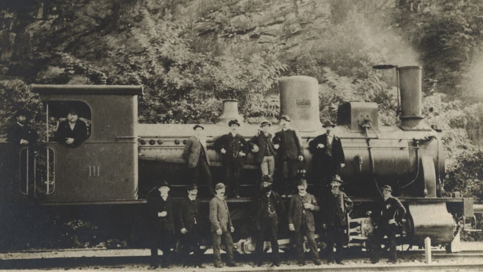 Männer stehen vor einer Dampflokomotive