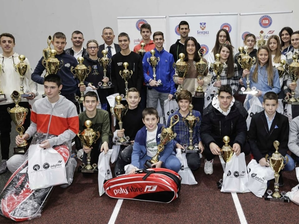 Viele Leute, keine Maske Novak Djokovic und die jungen Tennisspieler und -spielerinnen.
