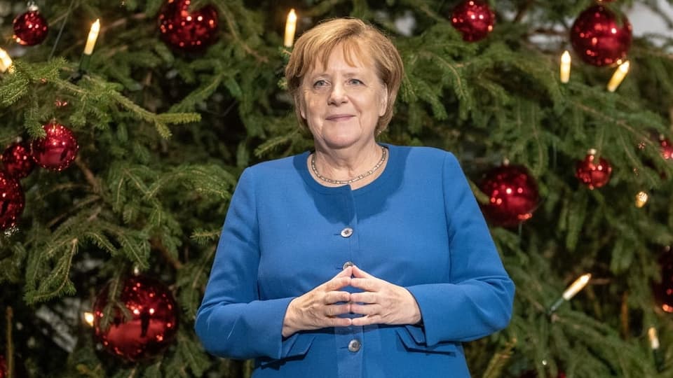 Merkel vor einem Weihnachtsbaum.