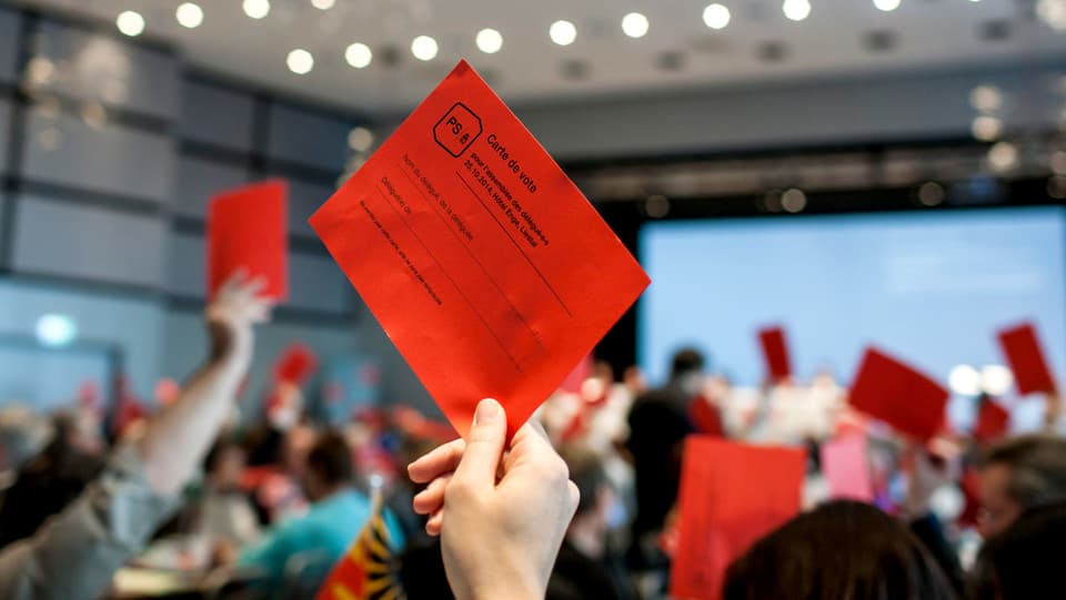 Eine Frau hält an der Versammlung der SP eine rote Wahlkarte in die Höhe.