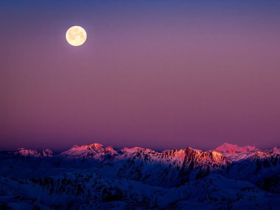 Violetter, wolkenloser Himmel über Schneebergen mit leuchtendem Vollmond