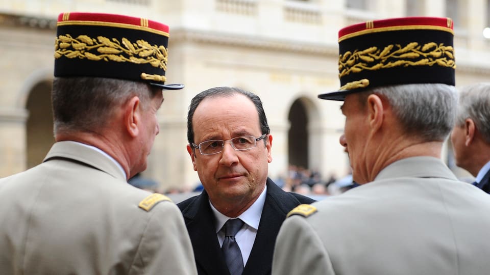 Präsident Hollande steht zwischen zwei Vertretern des Militärs