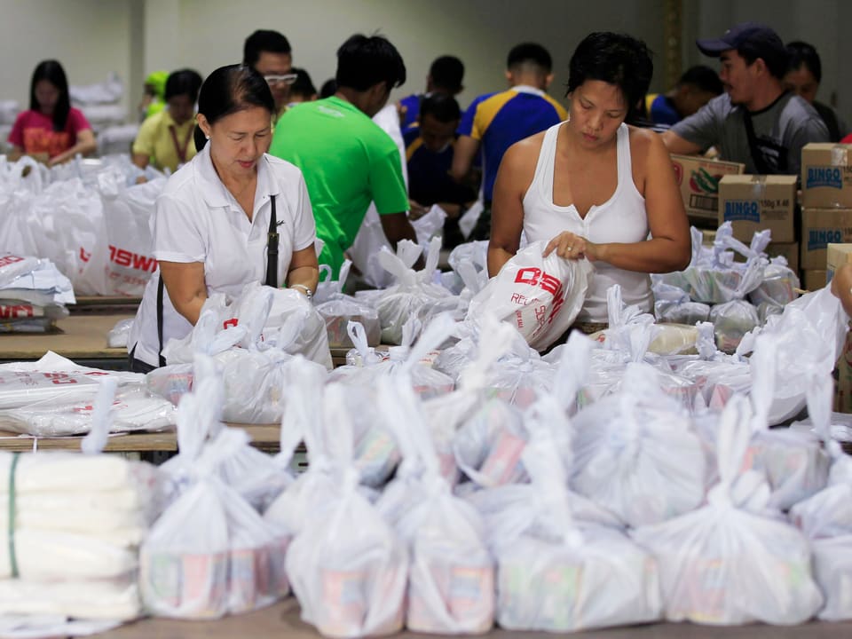 Personen packen Hilfsgüter in weisse Plastiksäcke