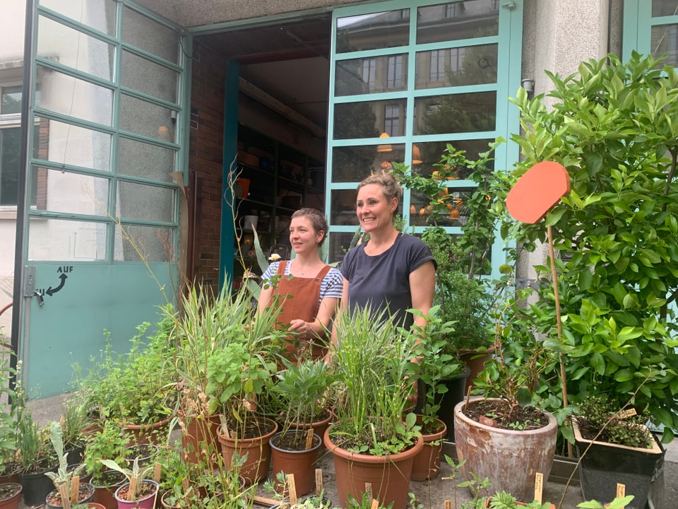 Die zwei Gründerinnen stehen inmitten von ihren Pflanzen.