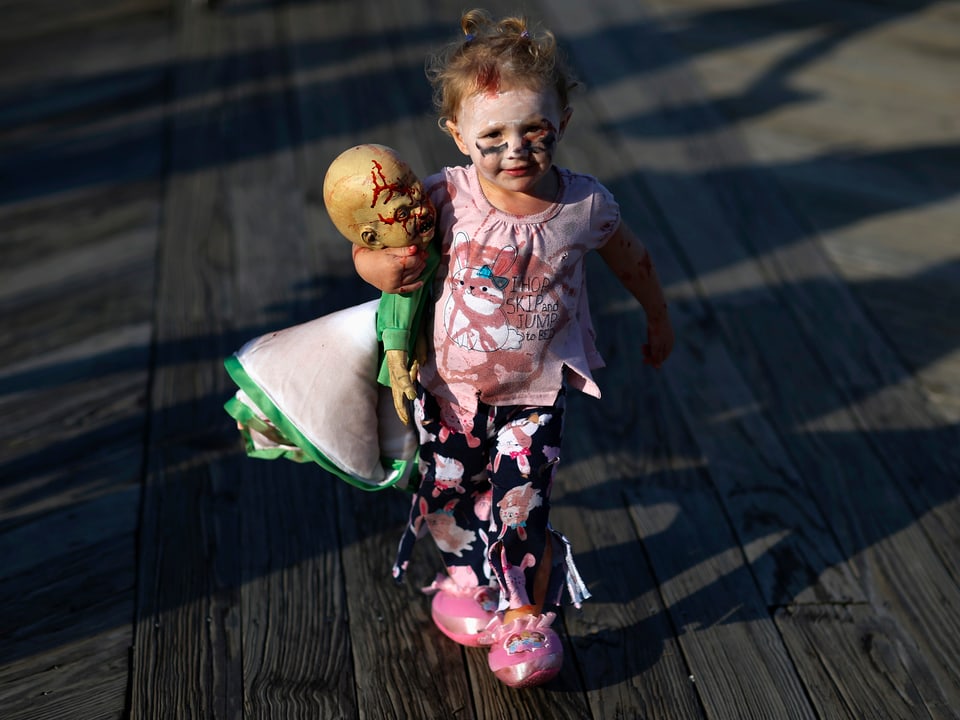 Kleines Zombiemädchen mit Zombie-Babypuppe.