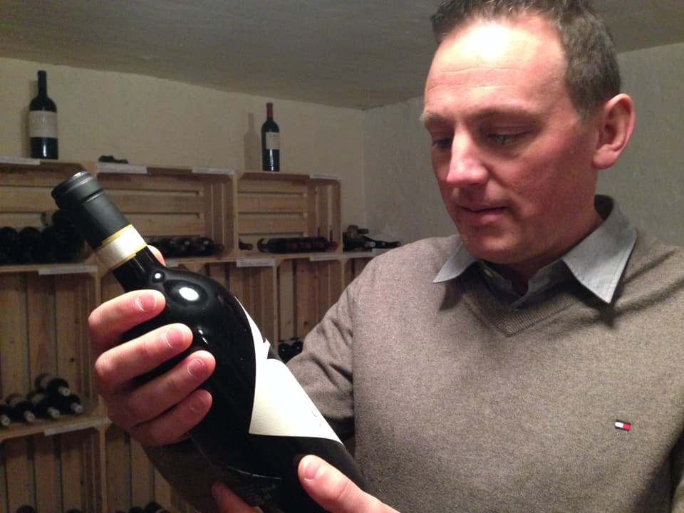 Samuel Kappeler betrachtet eine Flasche Wein.