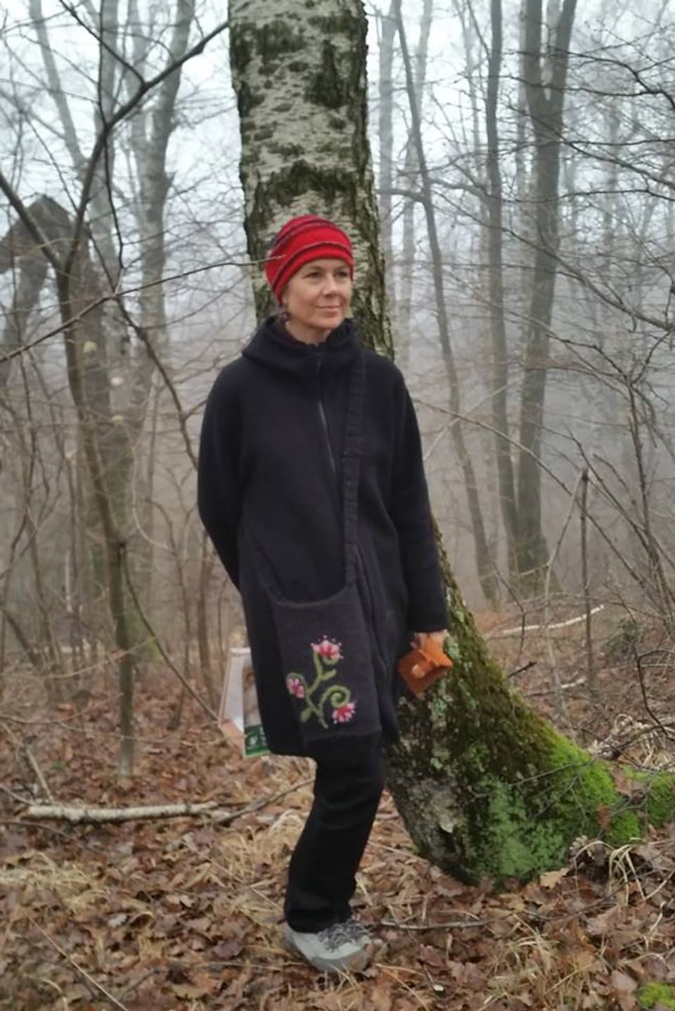 Frau im Wald mit roter Filzmütze.