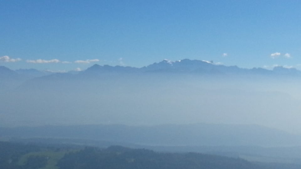 Bild vom Bachtel Richtung Glarner Alpen. Über den Bergen hat es ganz vereinzelt Quellwolken, und über dem Mittelland liegt Dunst.