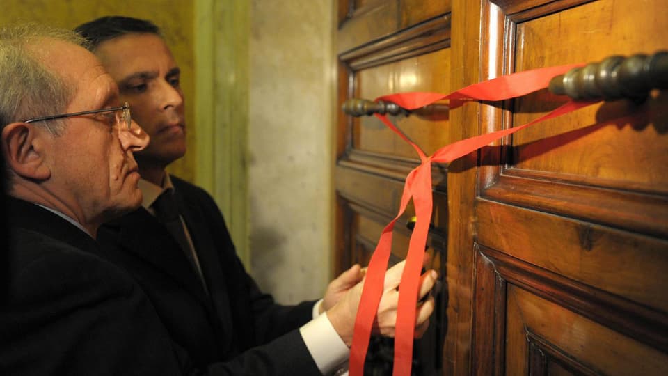 Angestellte des Vatikans verschliessen eine Tür symbolisch mit einem roten Band.