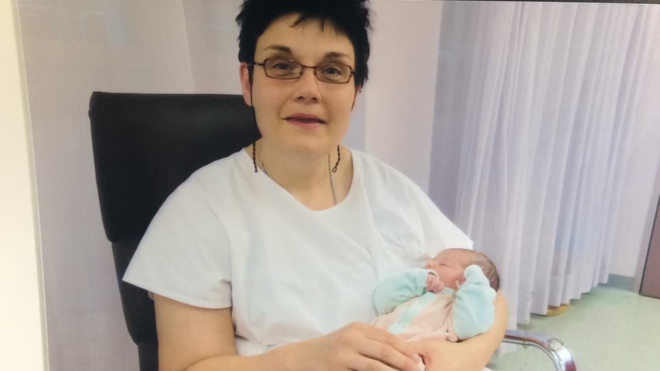 Sandra Fluri sitzt im Spital auf einem Stuhl und hält ein Baby in den Armen.