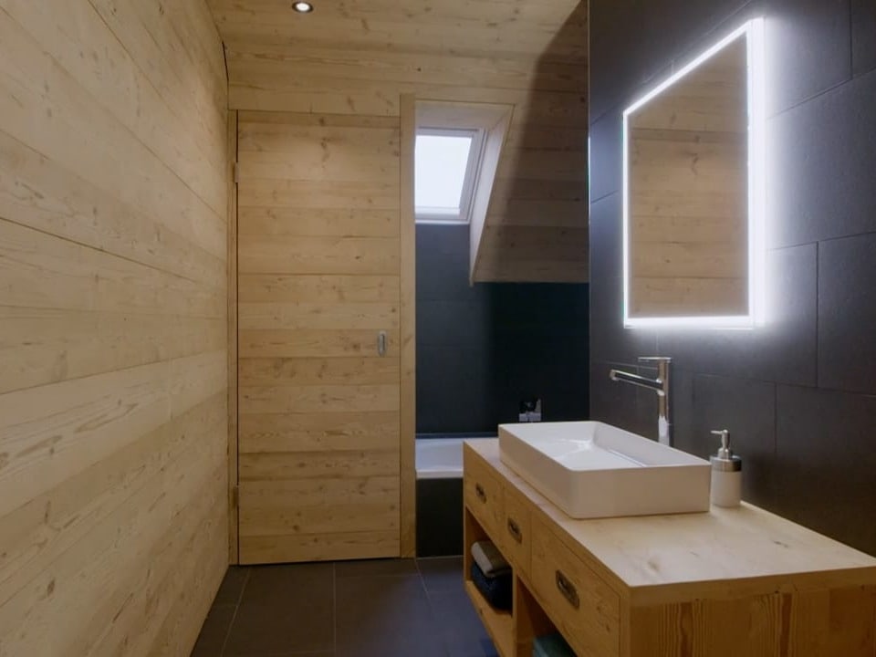 Ein helles Holz Badezimmer, die rechte Wand ist schwarz angemalt.