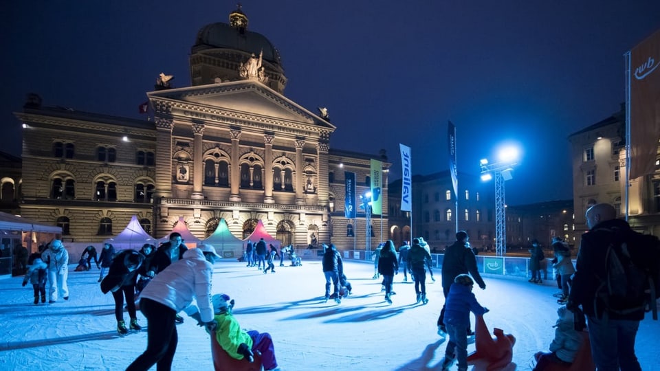Kinder und Jugendliche vergnuegen sich auf dem Eisplatz auf dem Bundesplatz.