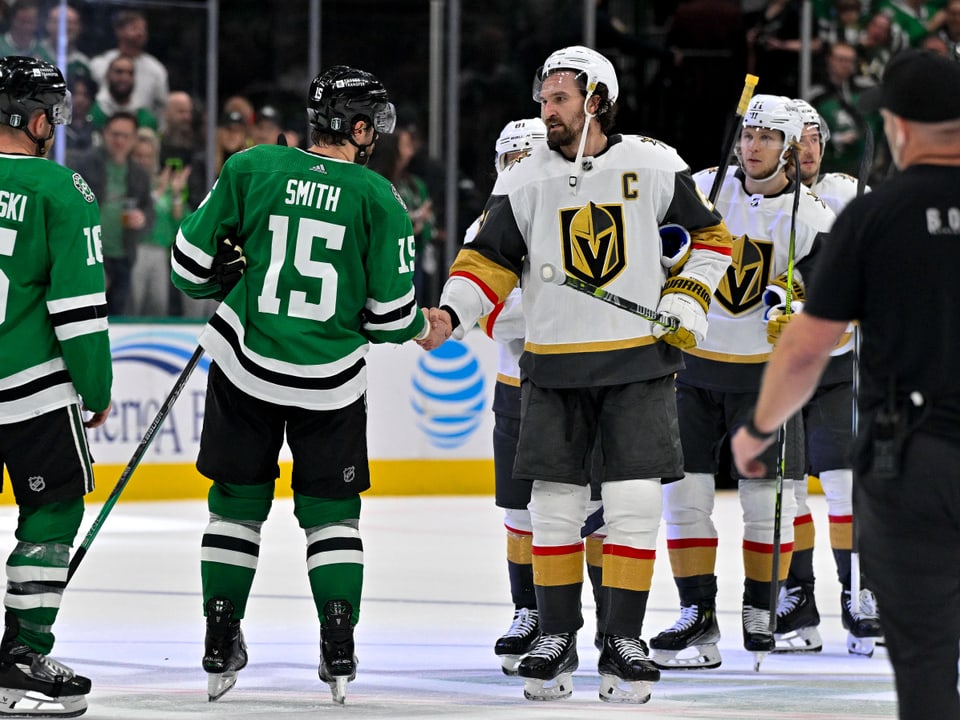 Eishockeyspieler in grünen und weissen Trikots begrüssen sich auf dem Eis.