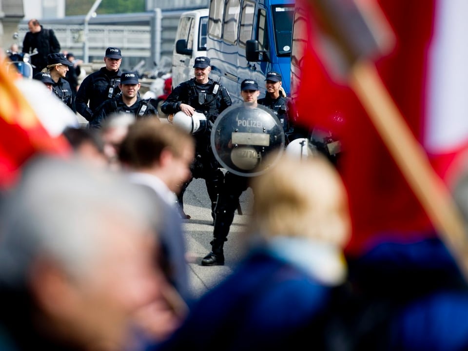 Demonstration, im Hintergrund Polizisten in Schutzkleidung
