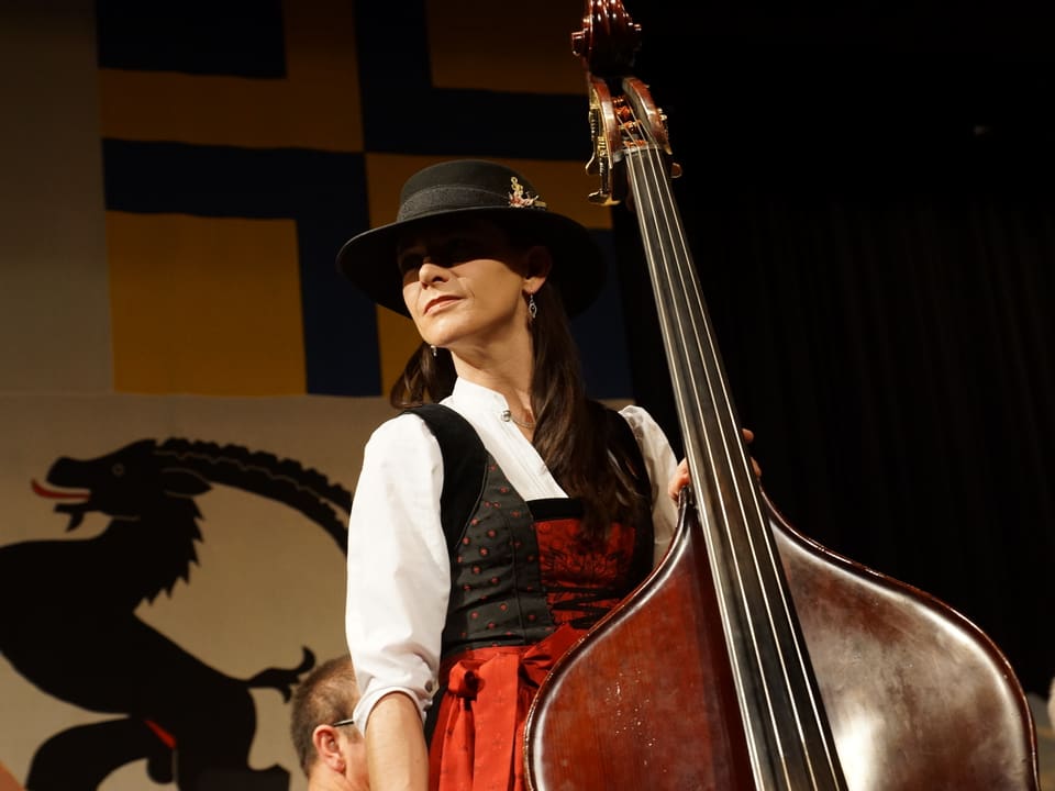 Eine Frau mit Hut und Tracht spielt Kontrabass.