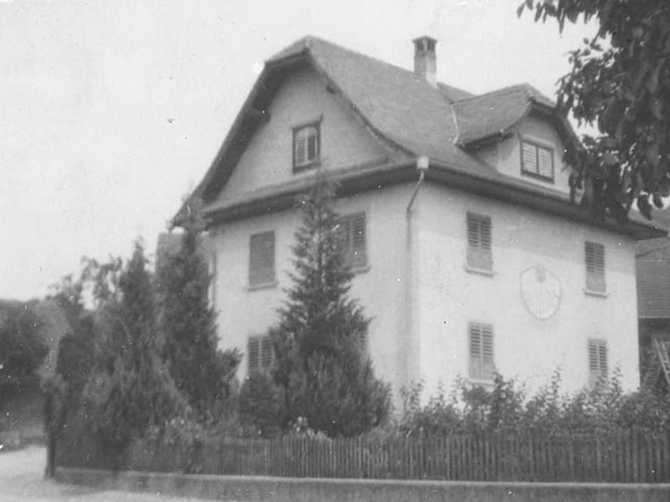 Schwarz-Weiss Fotografie mit einem dreistöckigen Haus an einer Strassenecke.
