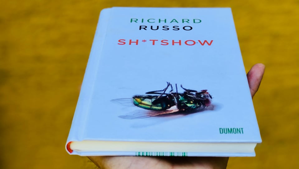 Das Buch «Sh*tshow» von Richard Russo vor einem ockerfarbenen Hintergrund