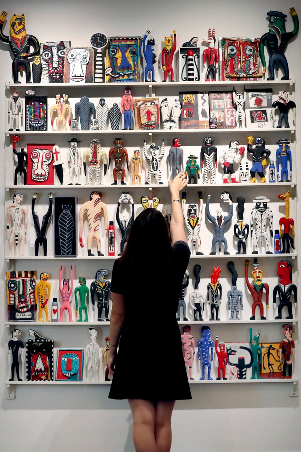 Eine Frau rückt die Figuren des Kunstwerks von Norman Catherine «Fanagalo Store» in Position.