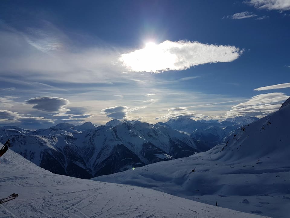 Verschneite Walliser Berge mit Schleier- und Föhnwolken am sonst blauen Himmel. 