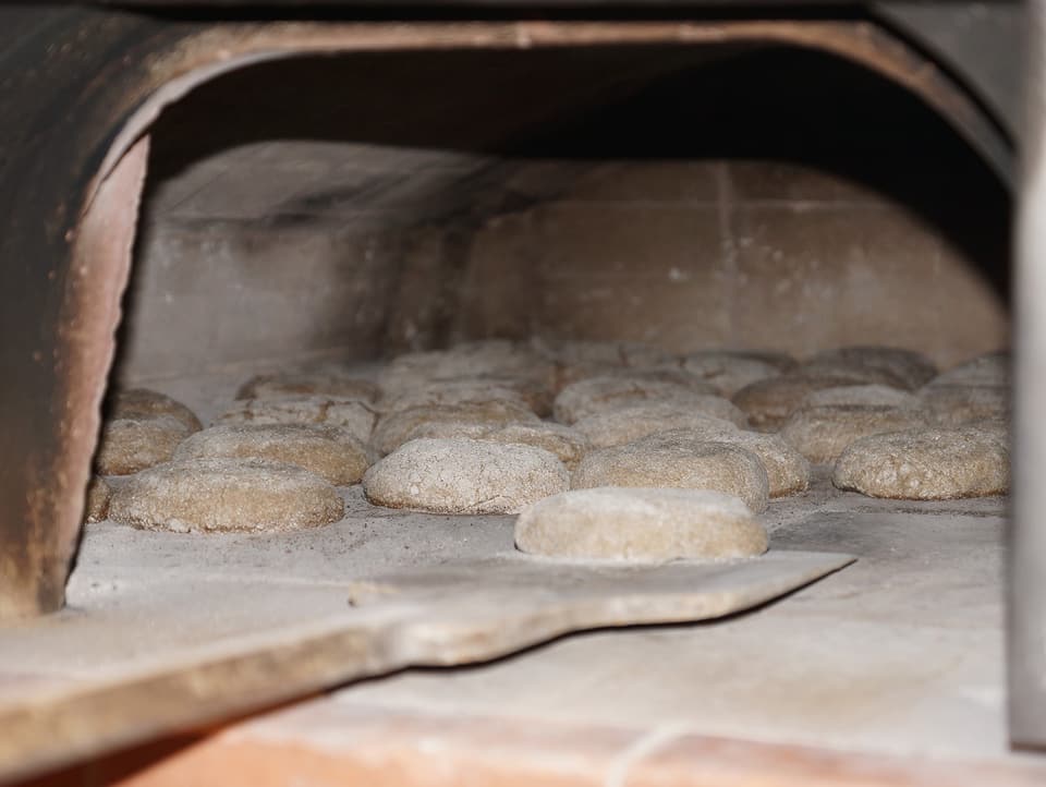 Brotlaibe werden in den Ofen geschoben.