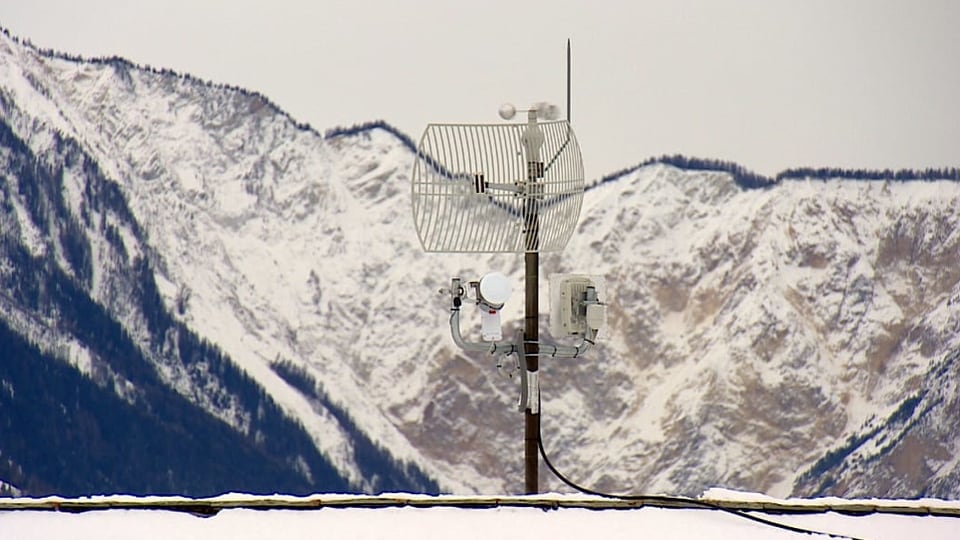 Antenne auf Hausdach, im Hintergrund ist ein Berg erkennbar