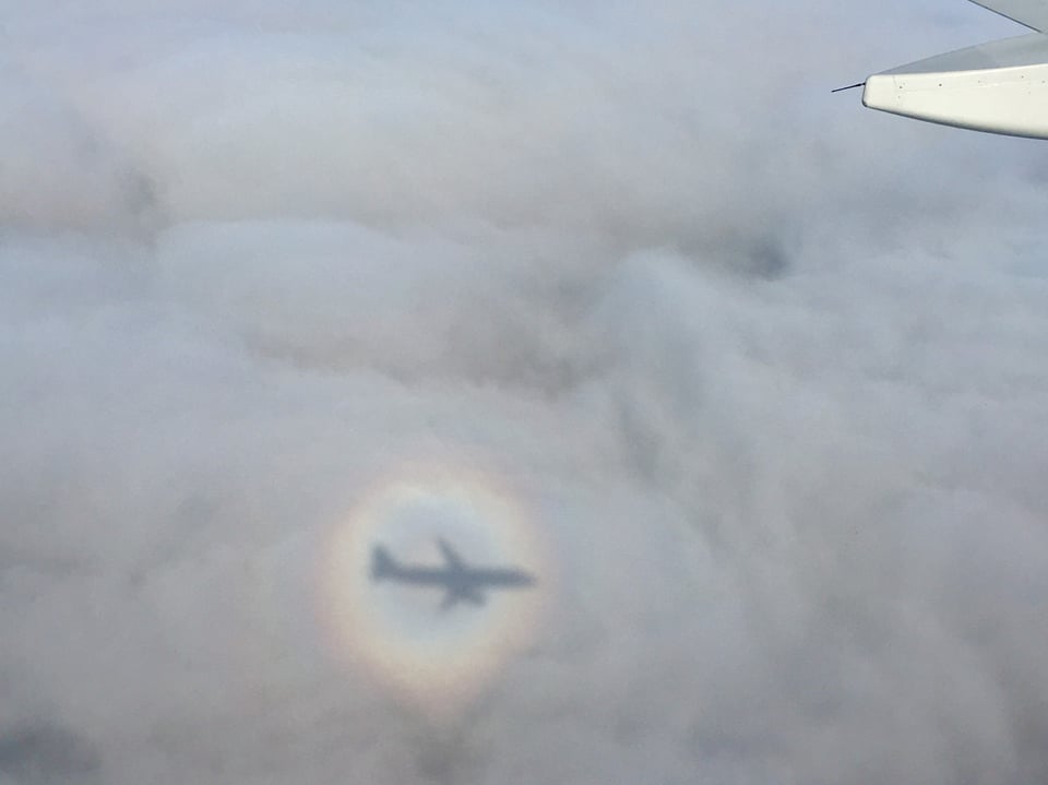 Der Schatten des Flugzeuges wird auf der Wolken- und Nebeldecke abgebildet.
