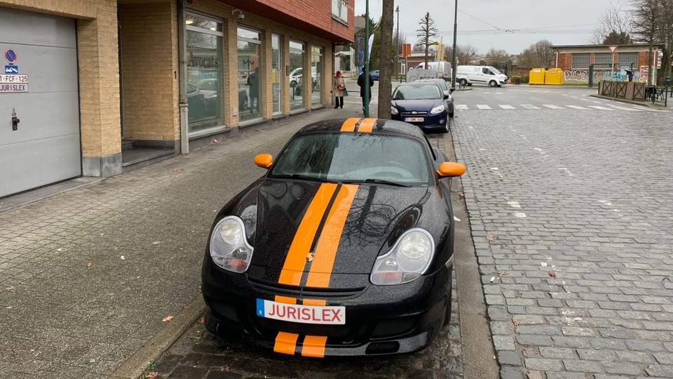 Ein schwarzer Porsche mit gelben Streifen steht am Strassenrand. 