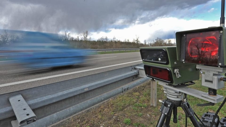 Blitzlichtanlage einer Radarkontrolle mit blauem Auto, das vorbei rast.