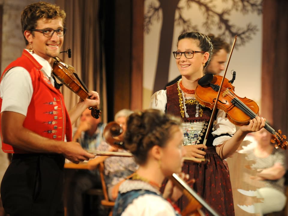 Riccarda und Damian Neff lächelnd mit Geigen in der Hand.