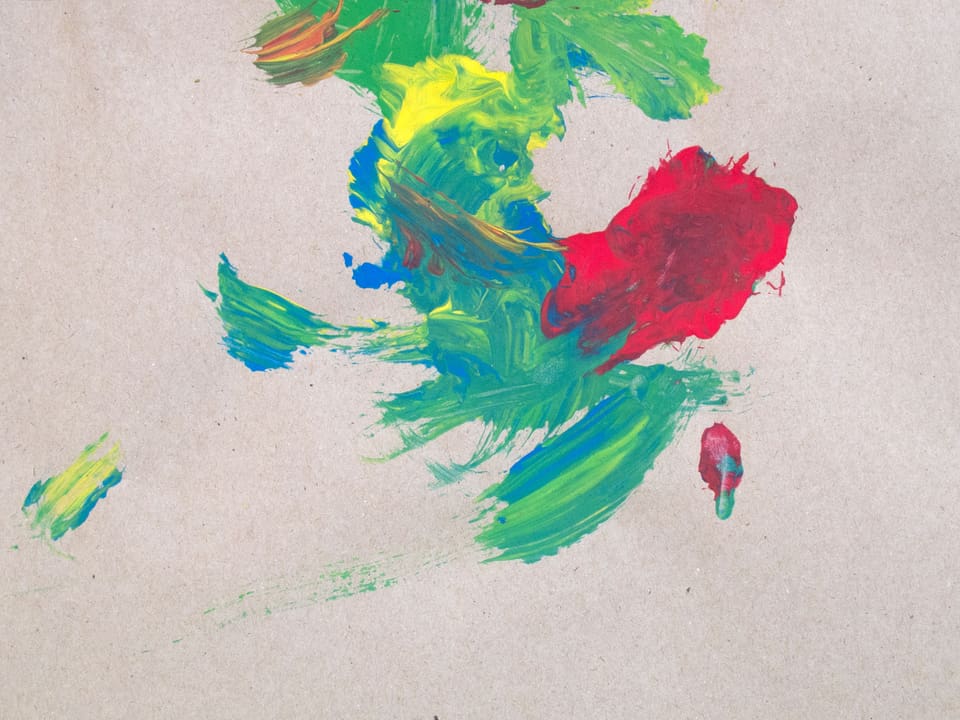 Auf einem Blatt Papier sind Farbkleckse in grün, blau, rot und gelb zu sehen.