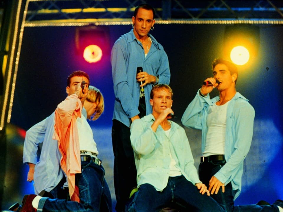 Boygroup posiert singend auf der Bühne