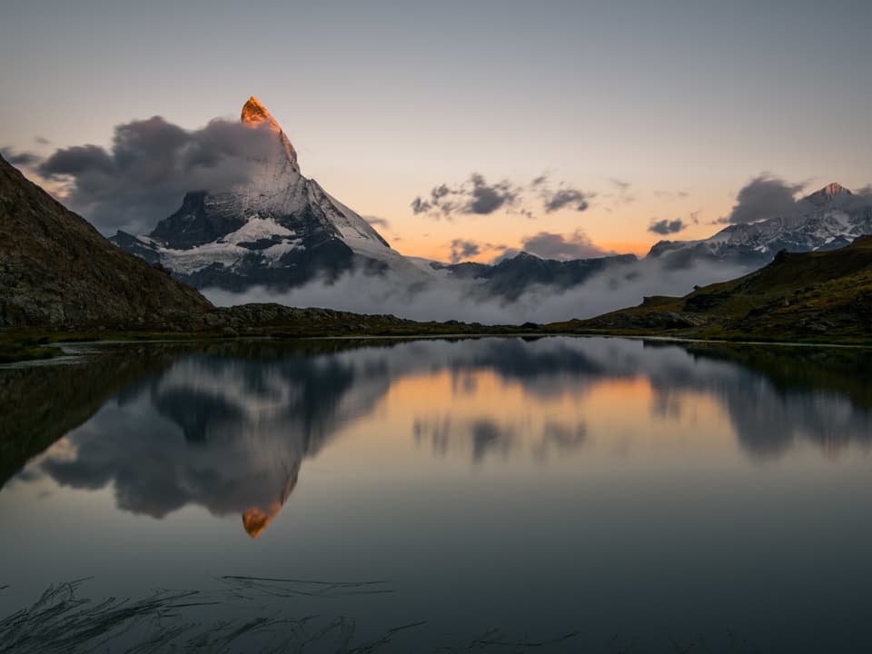 Morgenstimmung an einem Bergsee. Im Hintergrund das frisch verschneite Matterhorn, welches sich im See spiegelt.