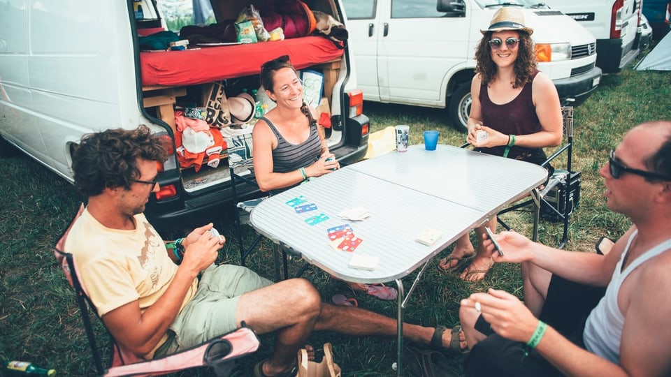 Menschen sitzen am Openair um einen Tisch und spielen Karte