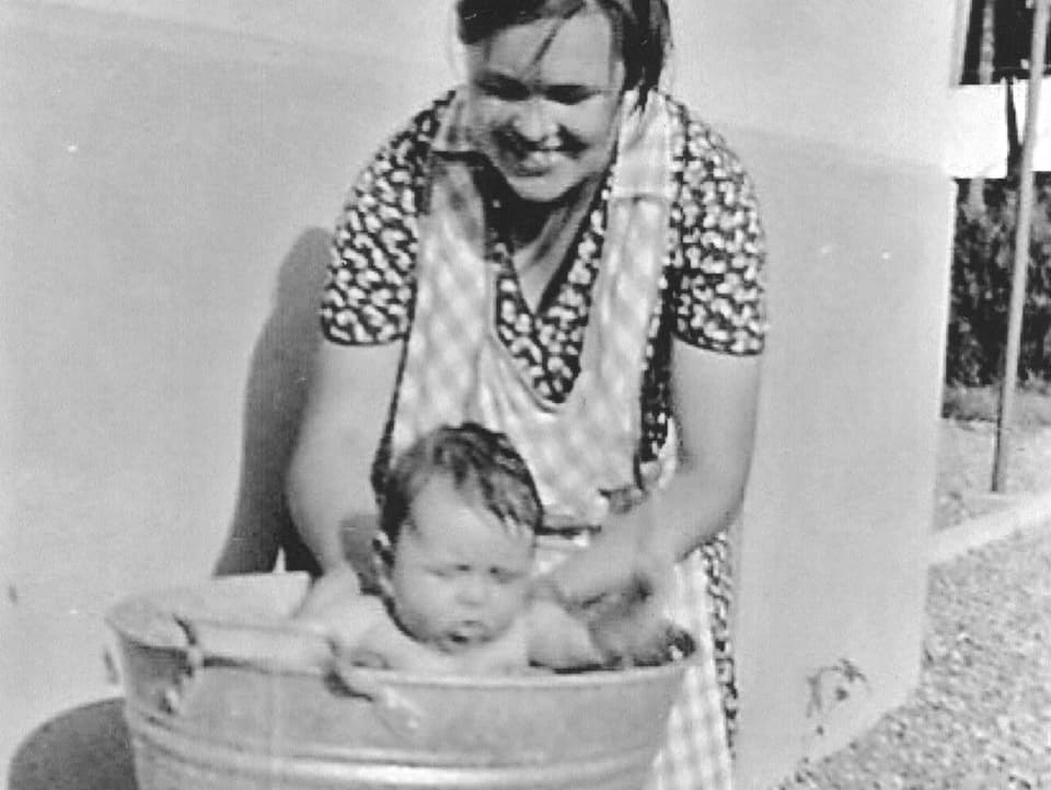 Mutter badet Kind in Waschtrog.