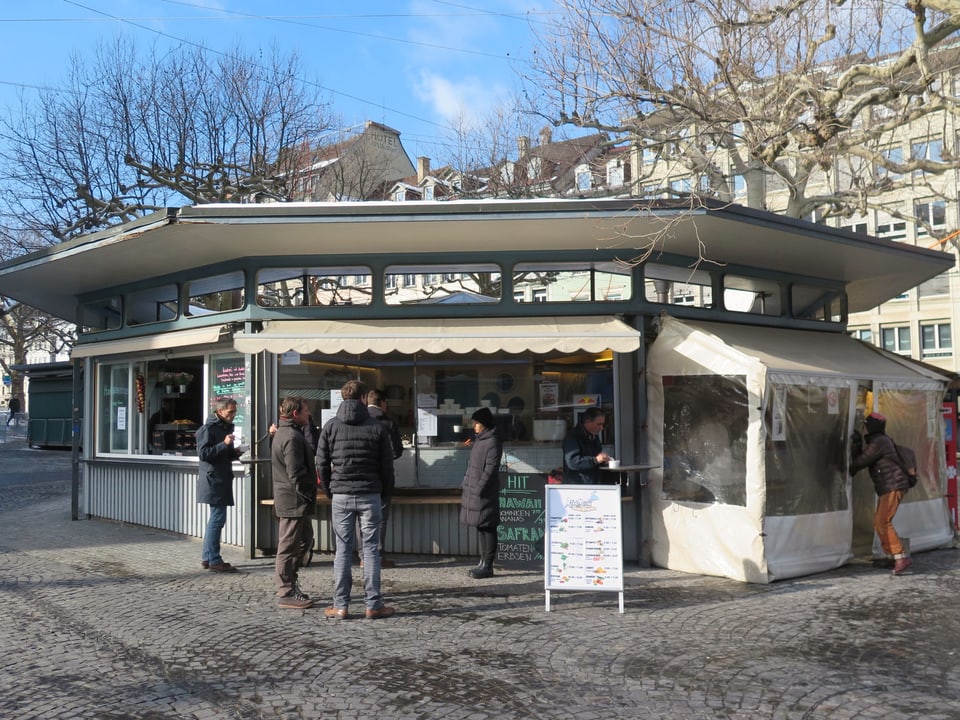 Die Rondelle von aussen. Leute stehen am Kiosk an. 