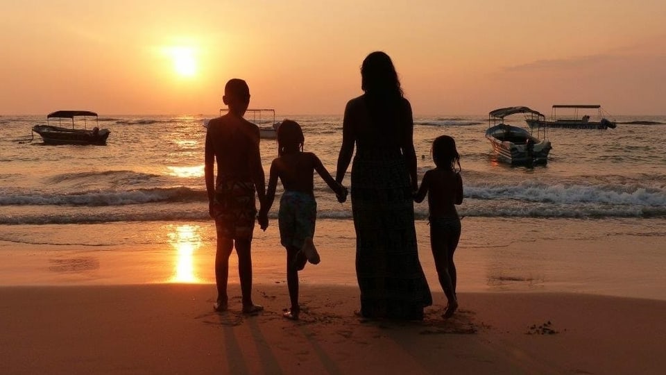 Eine Frau mit drei Kindern am Strand.