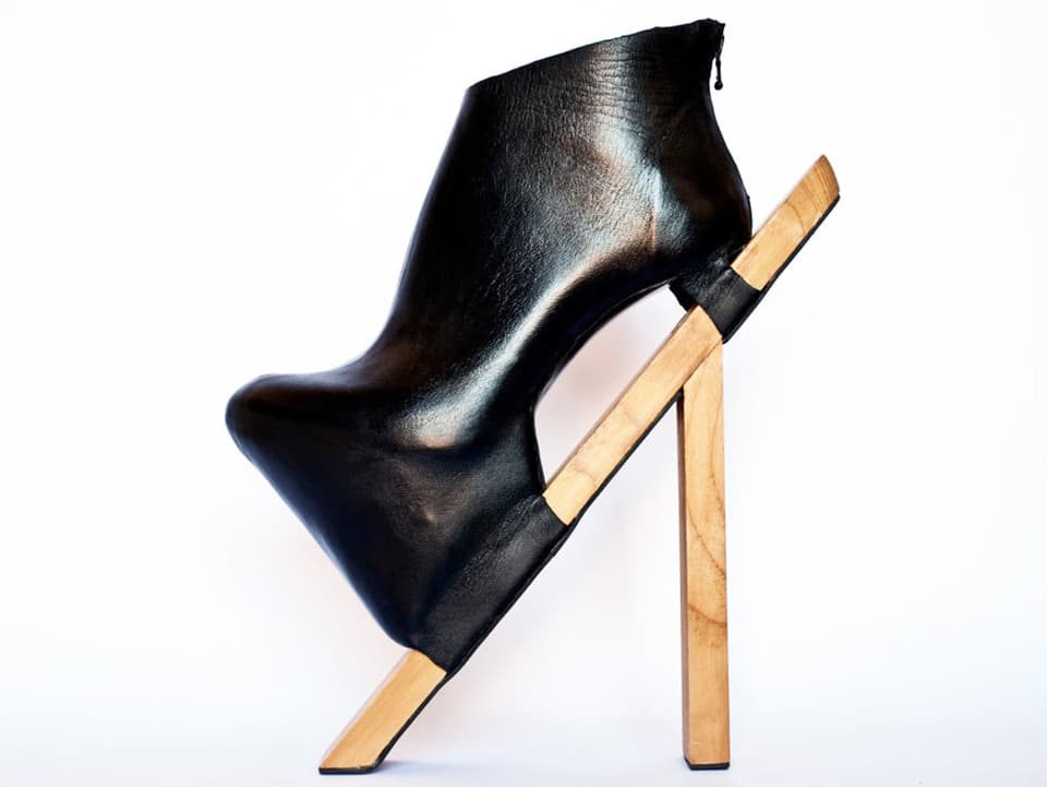 Ein schwarzer Schuh auf einem Holzstab.