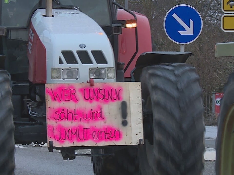 Ein Traktor mit einem Plakat, auf dem in pinken Buchstaben steht: «Wer Unsinn säht, wird Unmut ernten!*