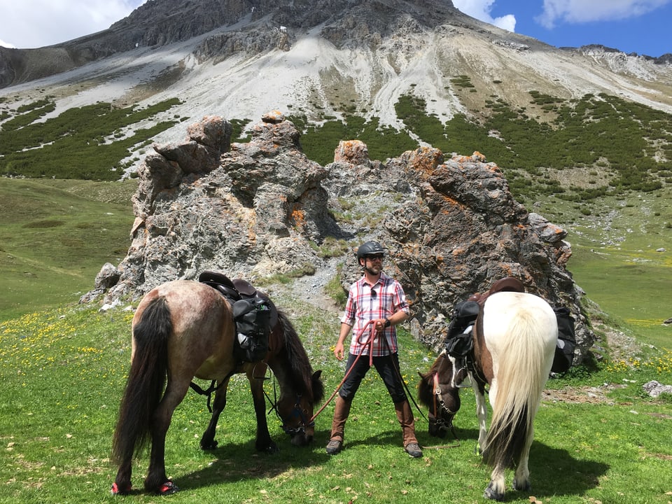 Nik mit zwei Isländer Pferden vor einem grossen Felsbrocken.