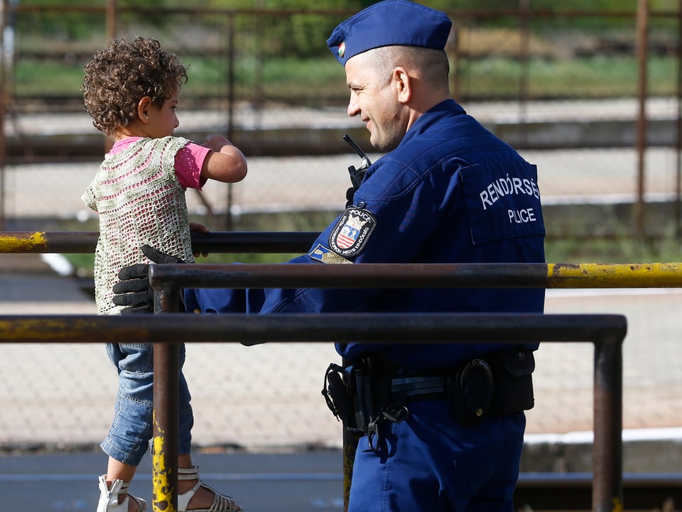 Ein ungarischer Polizist spielt an einem Bahnhof mit einem Flüchtlingsmädchen 