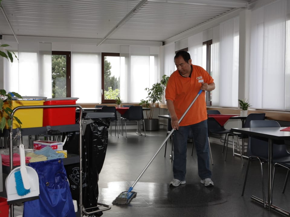 Ein Mann putzt den Boden eines Raumes.