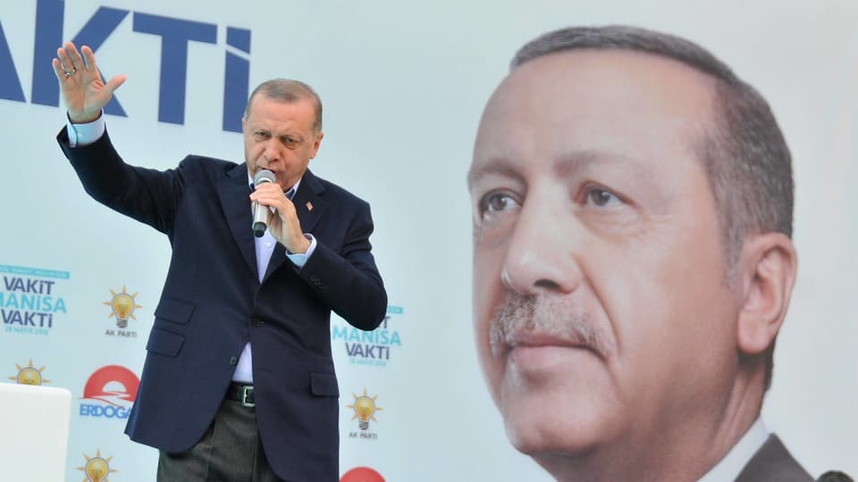 Erdogan sprichtin ein Mikrofon, hinter ihm ein rieisiges Porträt seiner selbst.