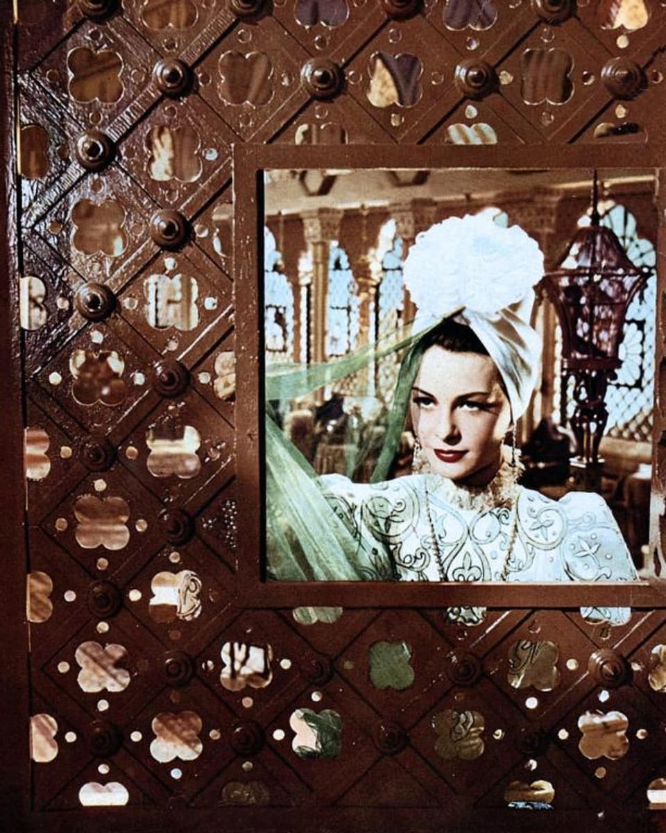 Ilse Werner blickt in der Rolle der Prinzessin Isabella d'Este durch eine Fenstergrosse Öffnung in der Wand eines grossen Zimmers.