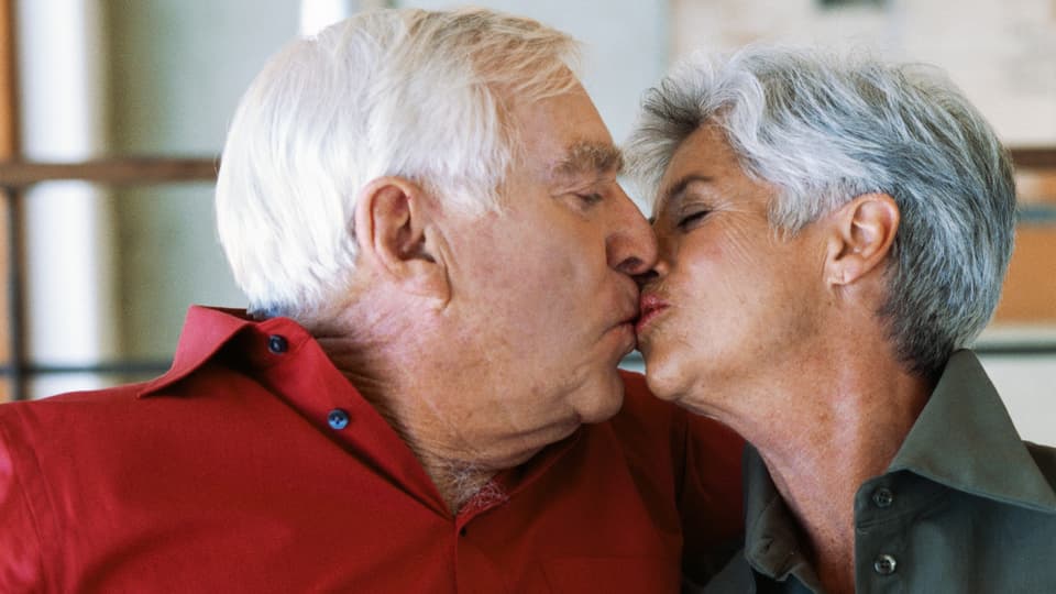 Ein älteres Paar küsst sich.
