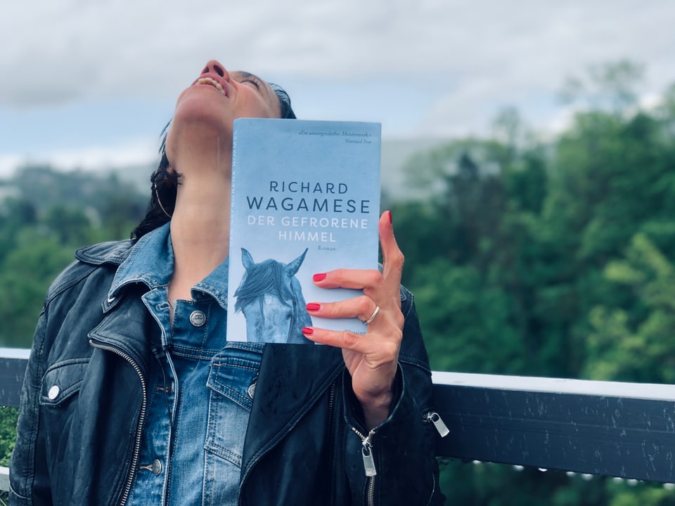 Annette König steht mit Richard Wagameses Roman «Der gefrorene Himmel» im Regen