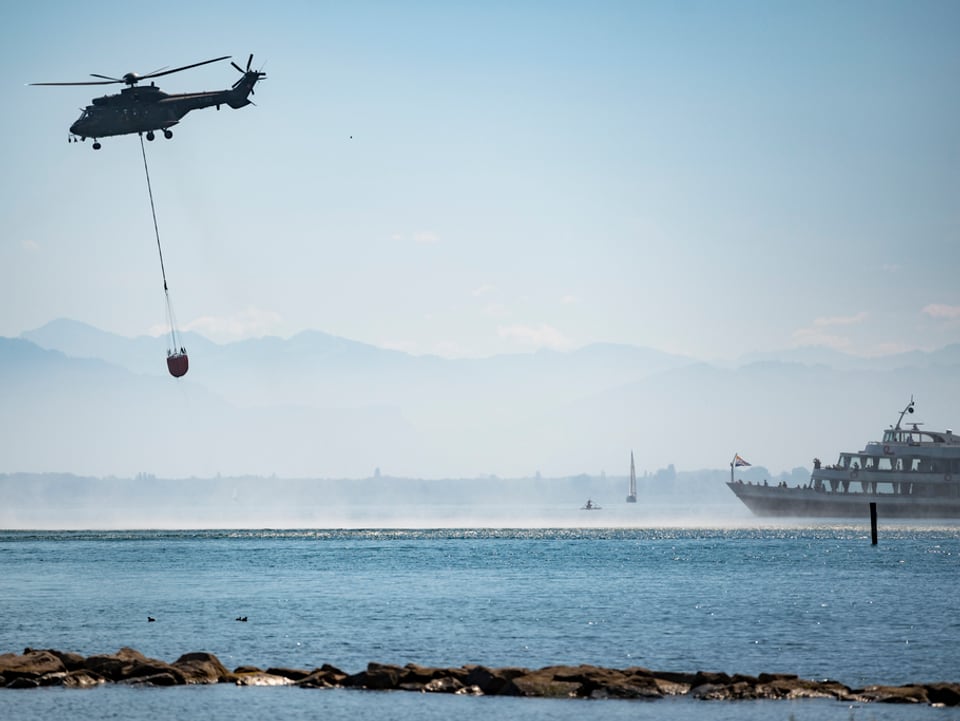 Ein Helikopter holt Wasser aus dem See.